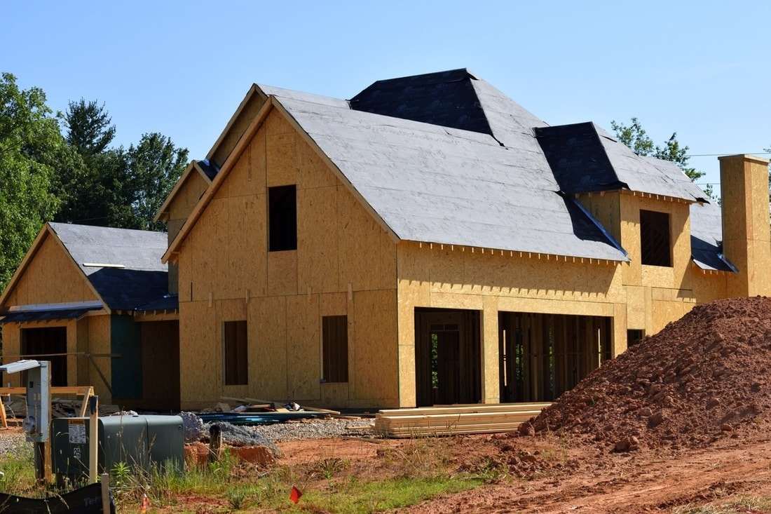 House under construction with exposed framing and surrounding earthwork