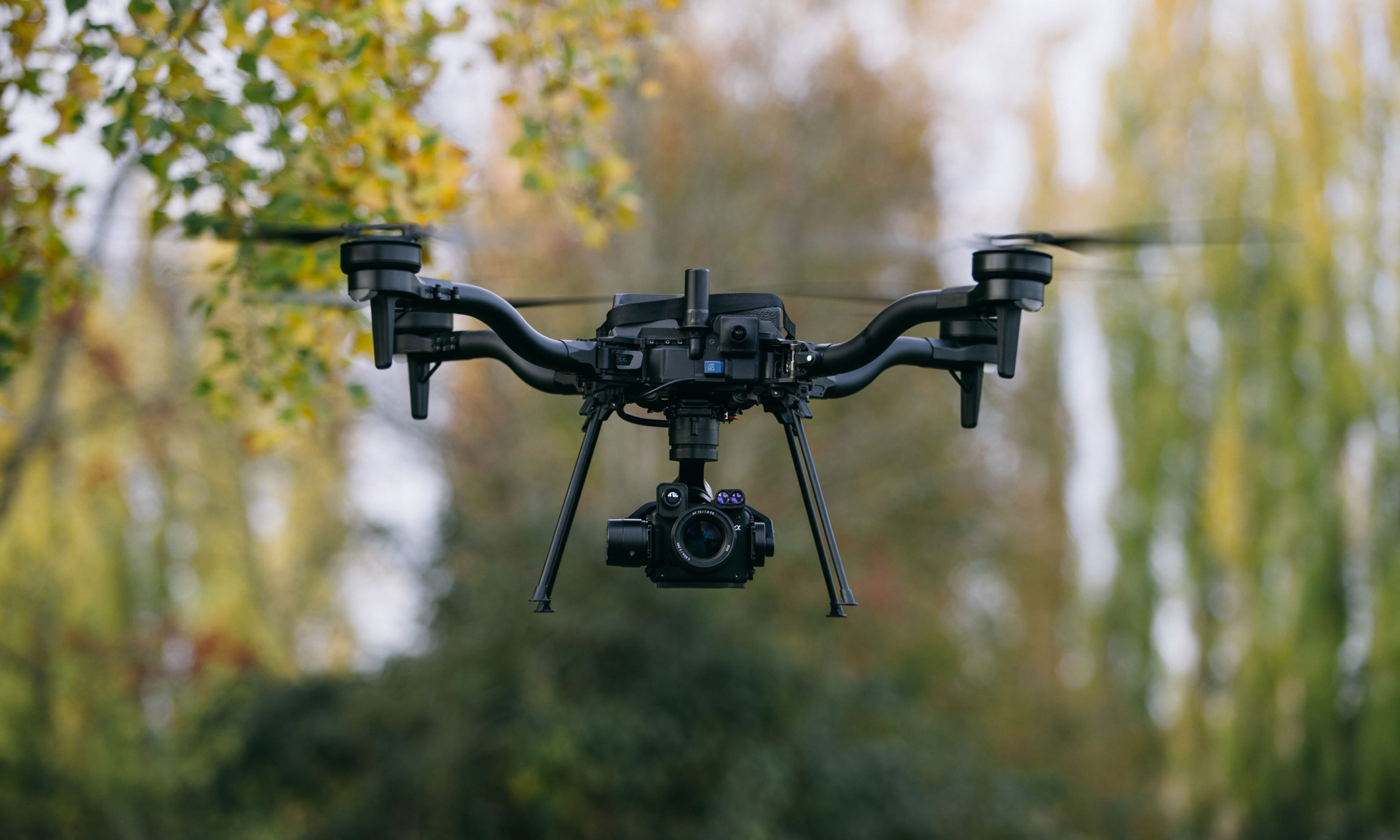 Freefly Astro flying beside woodland with a Sony camera gimbal and no LiDAR payload